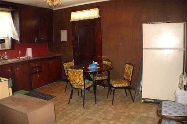 dining area with a chandelier and wood walls