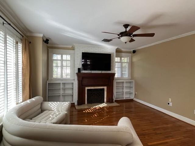 living room featuring dark hardwood / wood-style floors, a large fireplace, crown molding, and ceiling fan