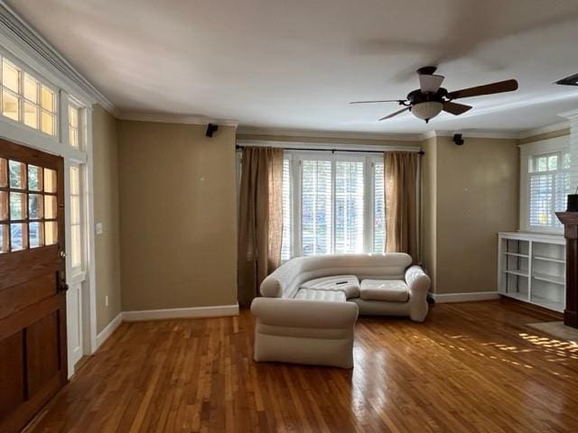 living area featuring hardwood / wood-style flooring, ceiling fan, and crown molding