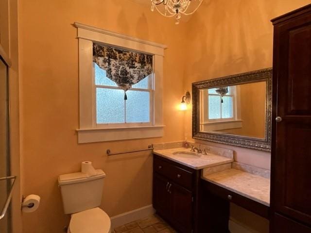 bathroom featuring vanity, toilet, a wealth of natural light, and a notable chandelier