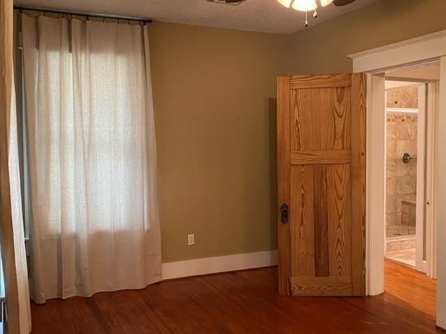 unfurnished bedroom with ensuite bathroom, dark wood-type flooring, and a textured ceiling