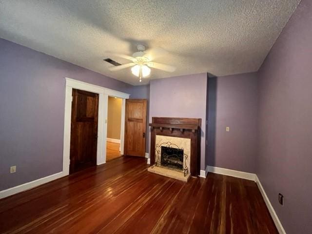 unfurnished living room with a textured ceiling, ceiling fan, and dark wood-type flooring