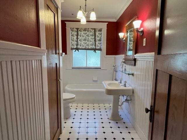 bathroom with a notable chandelier, toilet, ornamental molding, and a tub