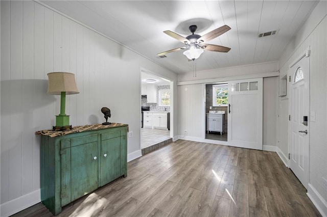 foyer with ceiling fan, wood walls, and hardwood / wood-style flooring