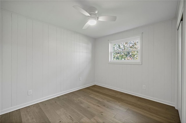 spare room featuring ceiling fan, light hardwood / wood-style floors, and wood walls