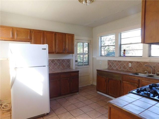 kitchen featuring white appliances, backsplash, tile counters, and sink