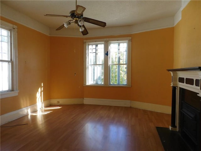 unfurnished living room with hardwood / wood-style floors, a textured ceiling, a wealth of natural light, and ceiling fan