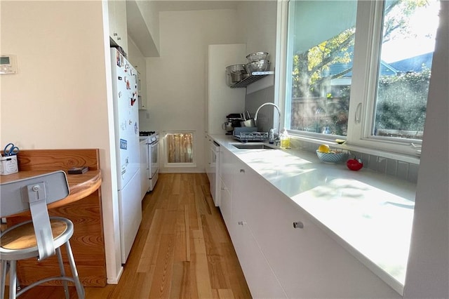 kitchen featuring white appliances, light wood-type flooring, white cabinetry, and sink