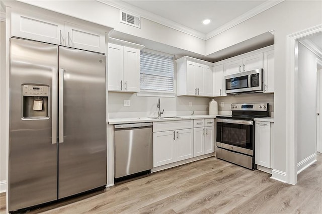 1908-10 St Louis St, New Orleans, LA 70112 - kitchen with stainless steel appliances, ornamental molding, light wood-style flooring, light countertops, and white cabinets