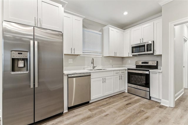 1908-10 St Louis St, New Orleans, LA 70112 - kitchen with stainless steel appliances, light countertops, white cabinetry, light wood finished floors, and crown molding
