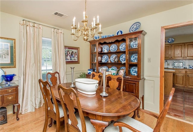 dining space with light wood-type flooring and an inviting chandelier