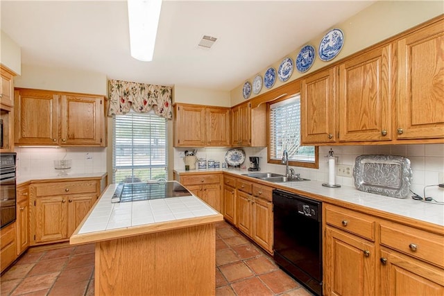 kitchen with a center island, black appliances, sink, a wealth of natural light, and tile counters