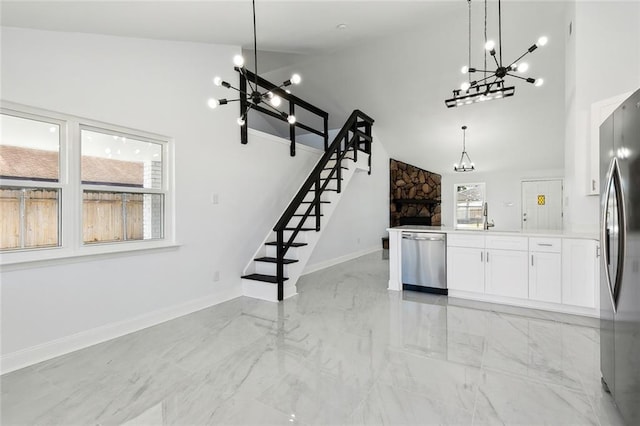 kitchen with appliances with stainless steel finishes, pendant lighting, high vaulted ceiling, a fireplace, and white cabinetry