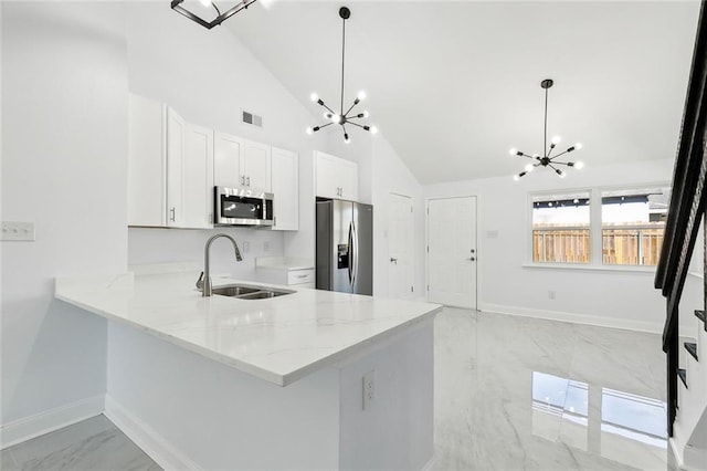 kitchen featuring sink, decorative light fixtures, appliances with stainless steel finishes, a notable chandelier, and kitchen peninsula