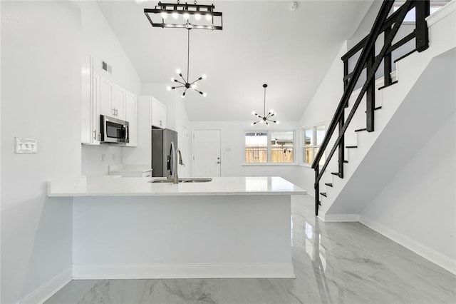 kitchen featuring kitchen peninsula, appliances with stainless steel finishes, sink, decorative light fixtures, and white cabinets