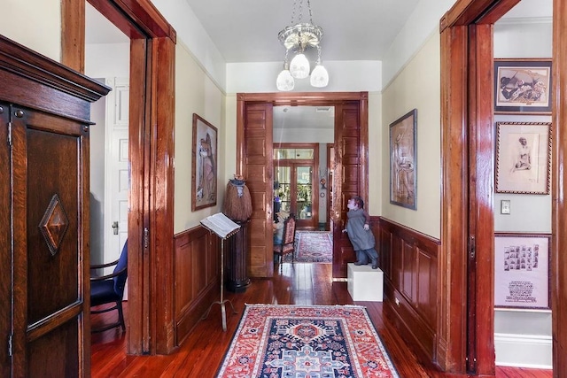 hall featuring french doors, dark hardwood / wood-style floors, and a notable chandelier