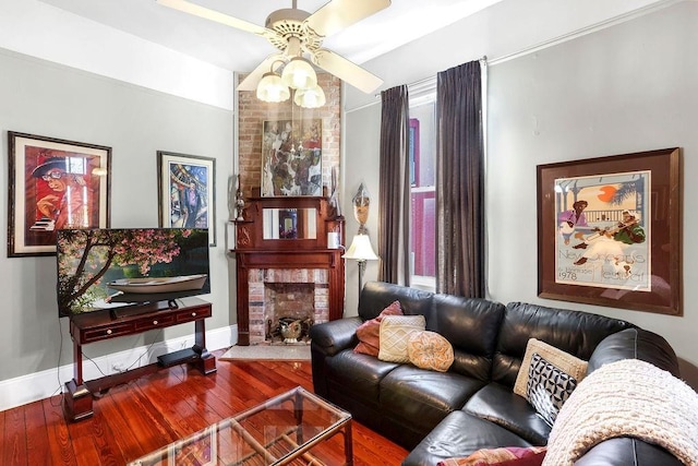 living room with ceiling fan, wood-type flooring, and a brick fireplace