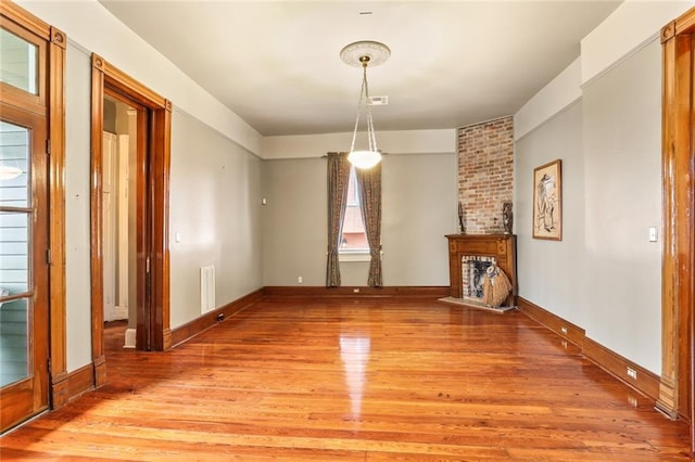 unfurnished living room featuring visible vents, light wood-style flooring, and baseboards