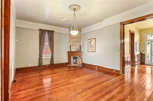 unfurnished living room with baseboards, a fireplace, visible vents, and wood finished floors