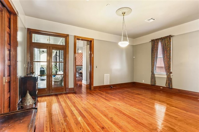 empty room featuring french doors, wood finished floors, visible vents, and baseboards