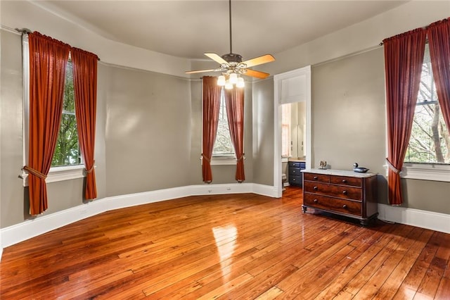 spare room featuring a ceiling fan, light wood-type flooring, a healthy amount of sunlight, and baseboards