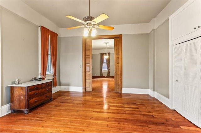 bedroom featuring a ceiling fan, light wood-type flooring, a closet, and baseboards