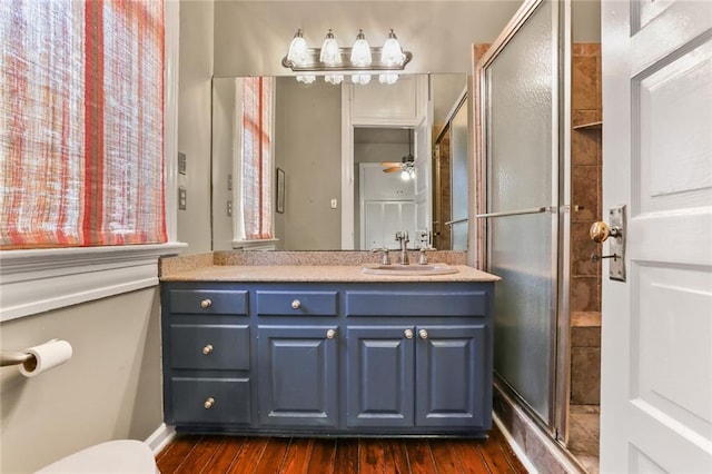 full bath featuring a stall shower, wood finished floors, vanity, and a ceiling fan