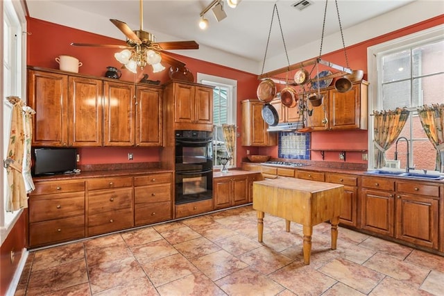 kitchen with stainless steel gas cooktop, brown cabinets, a sink, and dobule oven black