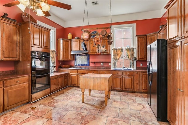 kitchen with visible vents, dark countertops, brown cabinets, black appliances, and a sink