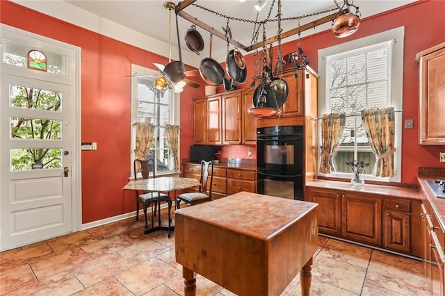 kitchen with brown cabinetry, plenty of natural light, a kitchen island, and dobule oven black