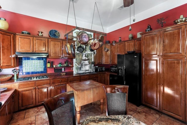 kitchen featuring dark stone counters, black fridge, sink, decorative backsplash, and stainless steel gas cooktop