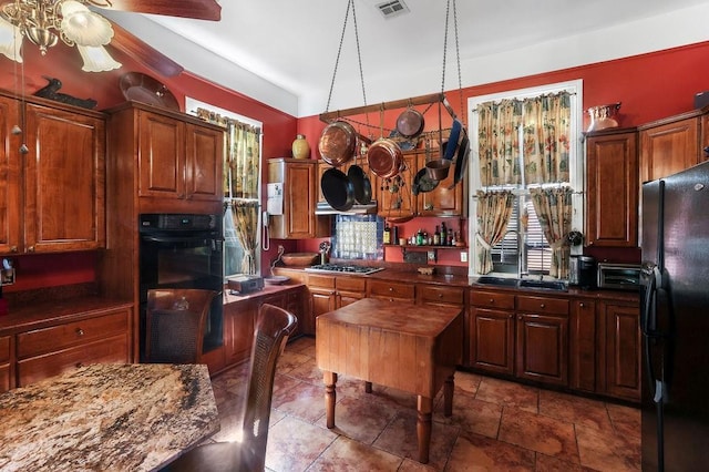 kitchen featuring a center island, ceiling fan, dark stone countertops, and black appliances