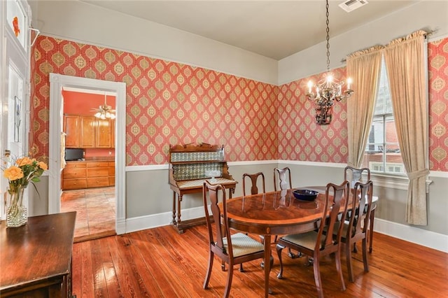 dining space with wallpapered walls, baseboards, and wood finished floors