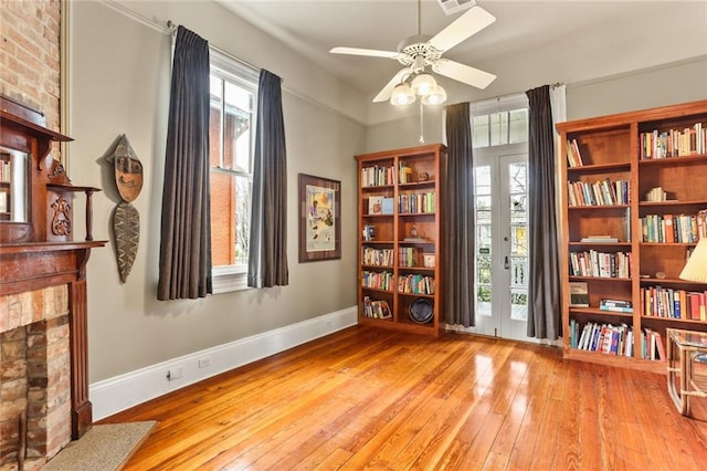 sitting room with light wood-style flooring, visible vents, baseboards, and a ceiling fan