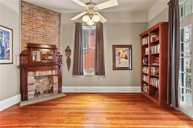 living area featuring light wood-style floors, plenty of natural light, baseboards, and ceiling fan