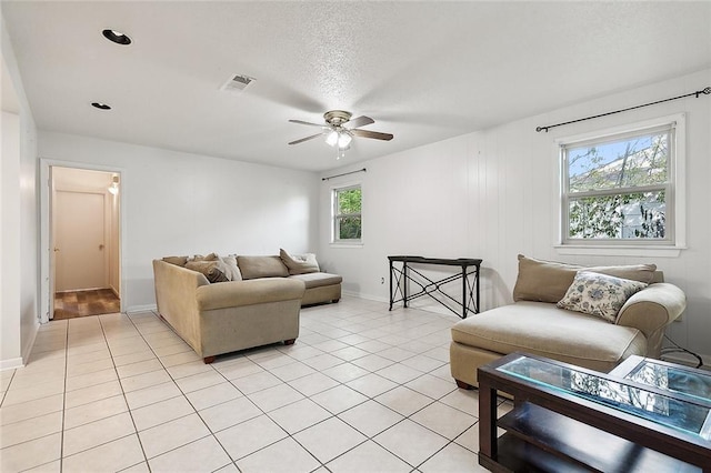 tiled living room with ceiling fan, plenty of natural light, and a textured ceiling