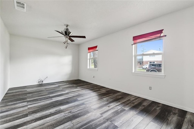 empty room featuring dark hardwood / wood-style floors, ceiling fan, and a wealth of natural light