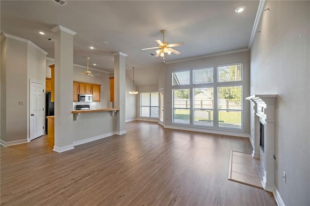 unfurnished living room with hardwood / wood-style flooring, ceiling fan, crown molding, and a tile fireplace