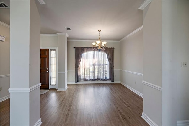 interior space with ornate columns, ornamental molding, dark wood-type flooring, and a chandelier