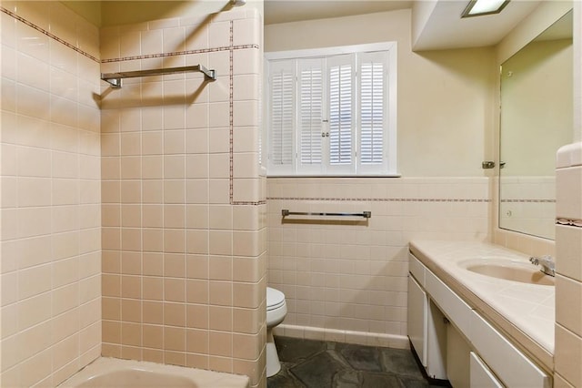 full bathroom featuring tiled shower / bath, vanity, tile walls, and toilet