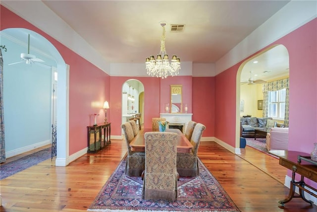 dining area with ceiling fan with notable chandelier and light hardwood / wood-style floors