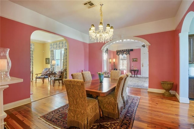 dining space with ceiling fan with notable chandelier and light wood-type flooring