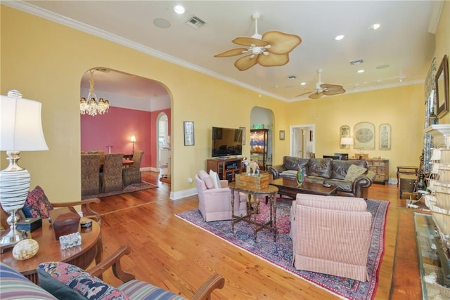 living room featuring hardwood / wood-style floors, ceiling fan with notable chandelier, and ornamental molding