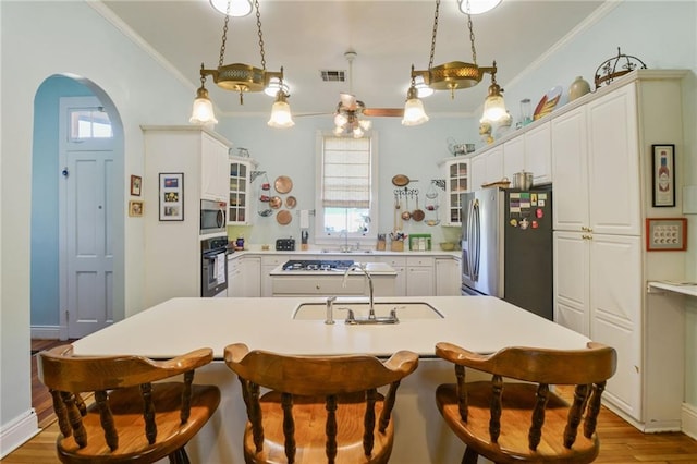 kitchen with plenty of natural light, wood-type flooring, a kitchen island with sink, and appliances with stainless steel finishes