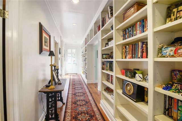 hallway with wood-type flooring and ornamental molding