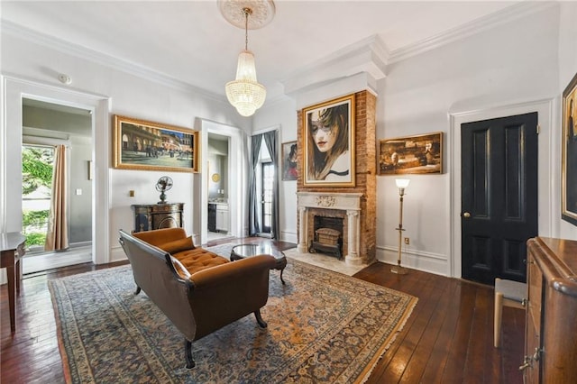 sitting room with crown molding, dark hardwood / wood-style flooring, a chandelier, and a brick fireplace