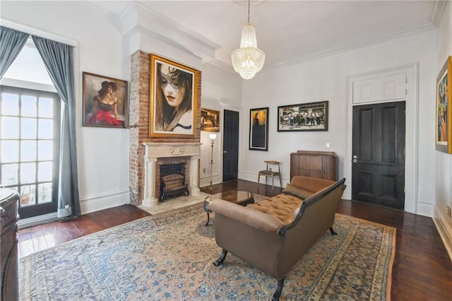 living room featuring crown molding, dark hardwood / wood-style flooring, a brick fireplace, and a notable chandelier