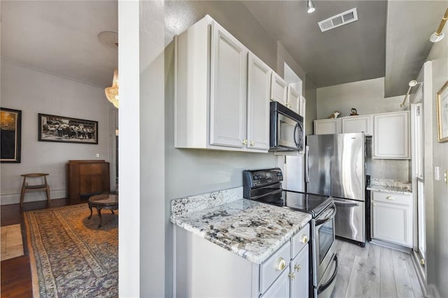 kitchen with light stone countertops, white cabinetry, appliances with stainless steel finishes, and light wood-type flooring