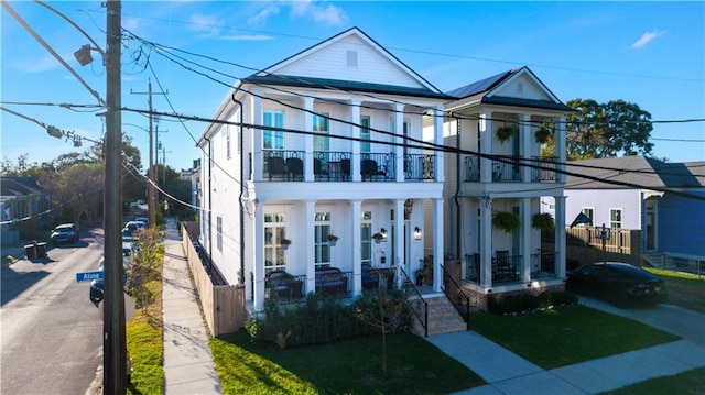 view of front of house featuring a balcony and a front lawn