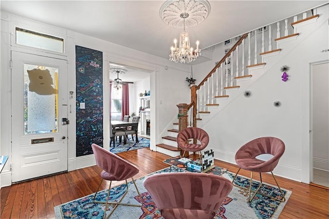 foyer entrance with hardwood / wood-style floors and ceiling fan with notable chandelier